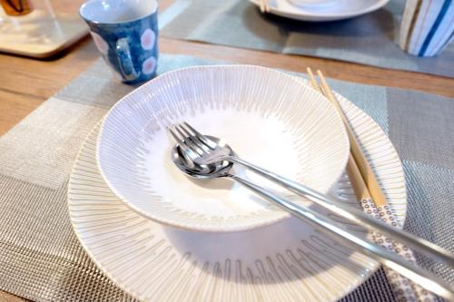 a white plate with a fork and knife on a table at 夢の舎代々木 Yumenoya Yoyogi in Tokyo