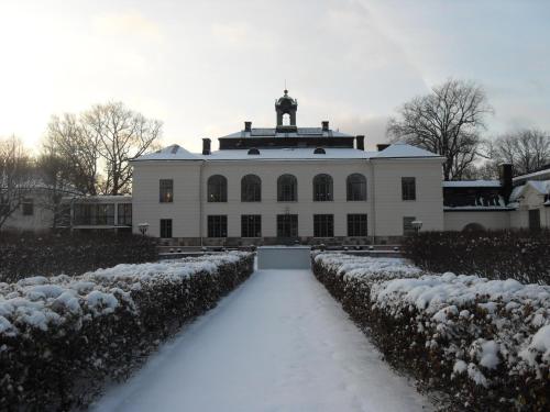 a white building with a snow covered driveway at Näsby Slott in Täby