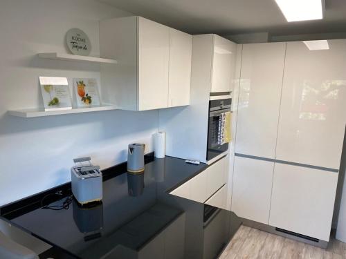 a kitchen with white cabinets and a black counter top at New York: Messe-/Business-/FeWo Düsseldorf/Hilden in Hilden