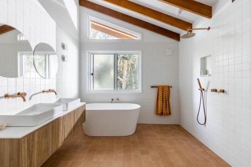 a bathroom with two sinks and a tub and a window at Blackbutt House - Luxe Retreat With Pool and Sauna in Suffolk Park