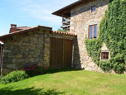a stone house with a wooden gate in a yard at Gîte de charme avec spa, sauna et jardin pour 12 personnes - FR-1-496-54 in Saint-Just-la-Pendue