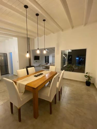 a dining room with a wooden table and white chairs at Casa en Costa Esmeralda in Costa Esmeralda