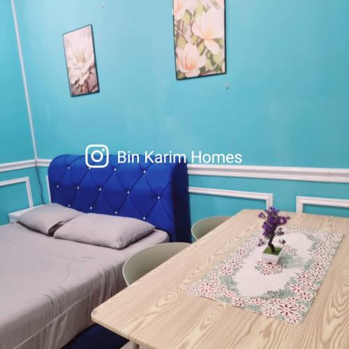 a room with a table with a bed and a blue wall at The Shore KK by Bin Karim Homes in Kota Kinabalu