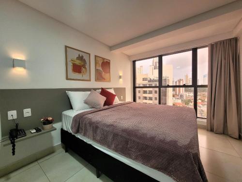 a bedroom with a large bed and a large window at Suíte no Manaíra Apart Hotel in João Pessoa