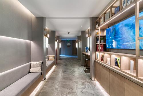 a hallway with benches and a tv in a room at True Go Hotel Shanghai Xujiahui in Shanghai