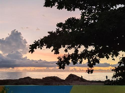 a sunset over the ocean with people on the beach at Sunset Seaview Bay Villa in Putatan