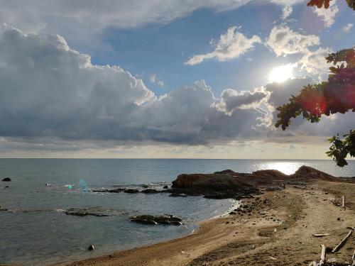 a beach with a cloudy sky and the ocean at Sunset Seaview Bay Villa in Putatan