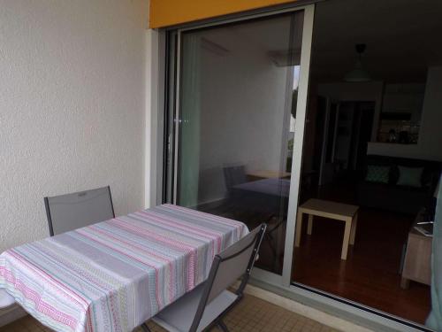 - une table et des chaises dans une pièce avec une porte coulissante en verre dans l'établissement Studio Coquet Proche Plage et Commerces, Terrasse, Parking, Clim, Wifi, Lave-Linge, Lave-Vaisselle - FR-1-328-221, à La Grande Motte
