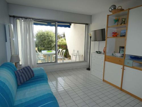 un salon avec un canapé bleu et une télévision dans l'établissement Studio Cabine en Rez-de-Chaussée - Vue Jardin & Mer, Quartier Calme - FR-1-328-265, à La Grande Motte