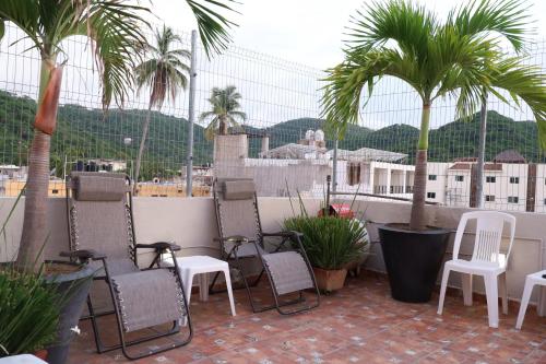 a group of chairs and palm trees on a balcony at Bungalows Yeah Los Ayala in Los Ayala