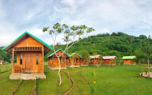 una fila di capanne di legno in un campo con una montagna di Beach Camp Bed & Breakfast a Gili Sudak