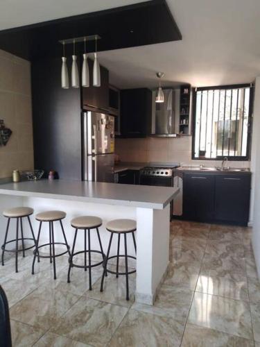 a kitchen with a large counter with stools around it at Hermoso, Apartamento zona Este in Barquisimeto