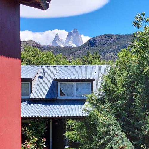 a house with a metal roof with mountains in the background at Hospedaje Mi Rincón El Chaltén in El Chalten