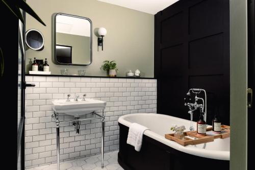 a bathroom with a white tub and a sink at Kimpton Clocktower by IHG in Manchester