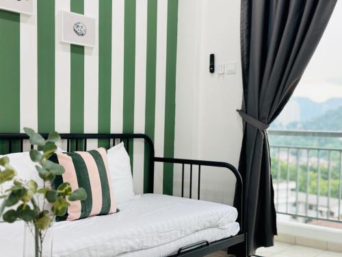 a bed in a room with a green and white striped wall at The Sun 1 or 3BR Bayan Lepas 4 to 10 pax WL in Bayan Lepas