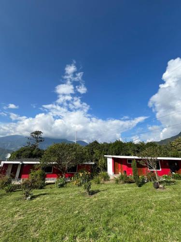 a red and white building in a field with trees at La Estancia de Runtún Km 7 in Baños