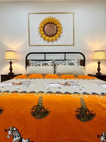 a bed with an orange comforter with a sunflower above it at Private Room Near Airport K2 in Mississauga