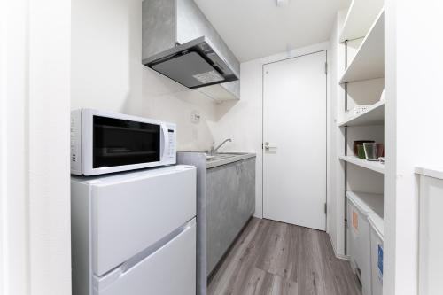 a kitchen with a microwave on top of a refrigerator at Omotenashi HOTEL Asakusa in Tokyo