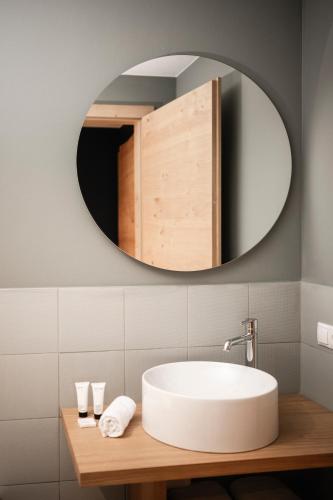a bathroom with a white sink and a mirror at The Post Mountain Residence in Dobbiaco