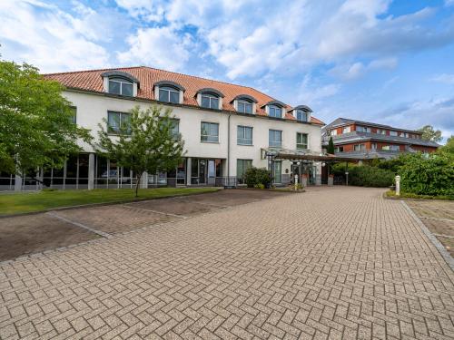 a large building with a brick driveway in front of it at Best Western Hotel Heidehof in Hermannsburg