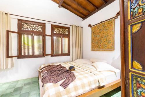 a bedroom with a bed in a room with windows at Joglo House in Central Bogor By penggemarlawas in Bogor