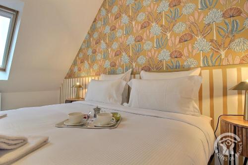 - un lit blanc avec deux tasses et des soucoupes dans l'établissement Face a tome, à Perros-Guirec