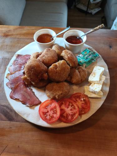 a plate of food with meat and onion rings and tomatoes at Chechar Inn Zlatar in Nova Varoš