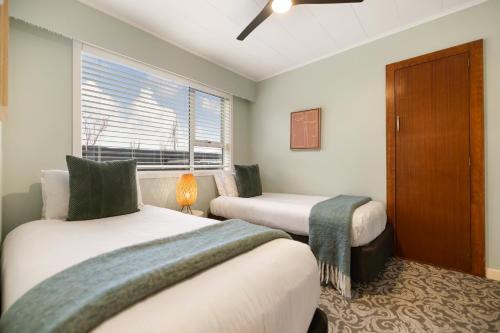 two beds in a room with a window at Arrowtown Motel in Arrowtown