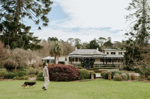 a man walking a dog in front of a house at Peppers Craigieburn Resort in Bowral