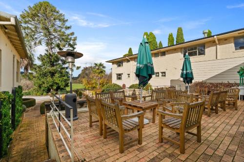 a patio with tables and chairs with umbrellas at Peppers Craigieburn Resort in Bowral
