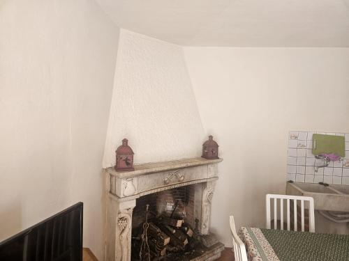 a fireplace in a living room with two vases on top of it at CASA SANT`ANNA DI STAZZEMA in Culla