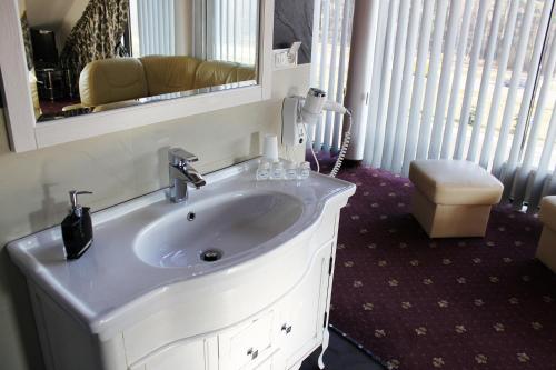a bathroom with a white sink and a mirror at Hotel Monet & Rubbens in Toruń