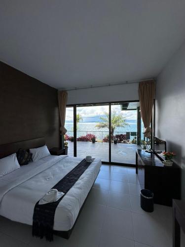 a bedroom with a large bed with a view of the ocean at Tiara Bunga Hotel & Villa in Balige