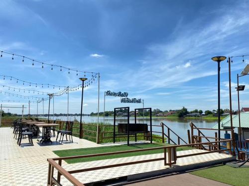 a patio with tables and chairs next to a body of water at Suwanna Riverside in Chai Nat