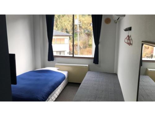 una camera da letto con un letto blu e una finestra di Biz Hotel Kiyura - Vacation STAY 93177v a Yura