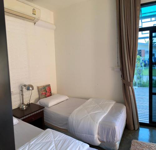 a hotel room with two beds and a window at Chiangmai Courtyard Residence บ้านสวนสวย บ้านถวาย in Bān Sawan