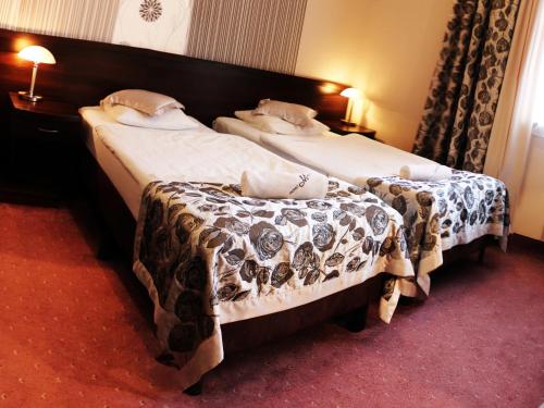 two twin beds in a hotel room withskirts at Hotel Monet & Rubbens in Toruń