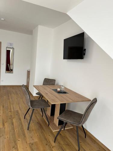 a dining room with a table and chairs and a tv at Apartments und Zimmervermietung in Liesingthal