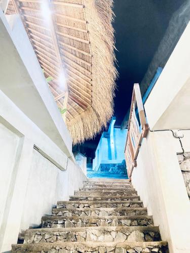 a staircase in a building with a straw roof at Sky Mountain Views in Kuta Lombok