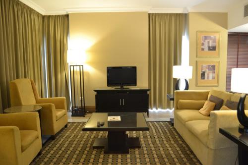 a living room with a couch and chairs and a tv at Sheraton Khalidiya Hotel in Abu Dhabi