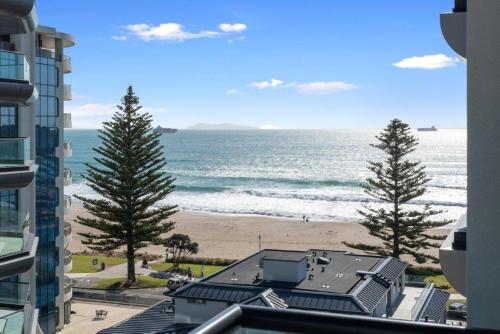 a view of the beach from a building at Superb Elevated Views of Harbour with Heated Pool, Gym & Parking in Mount Maunganui