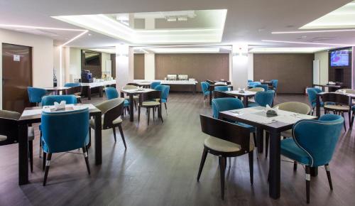 a dining room with tables and blue chairs at The Fifth Floor by Old Town Hotel in Timişoara