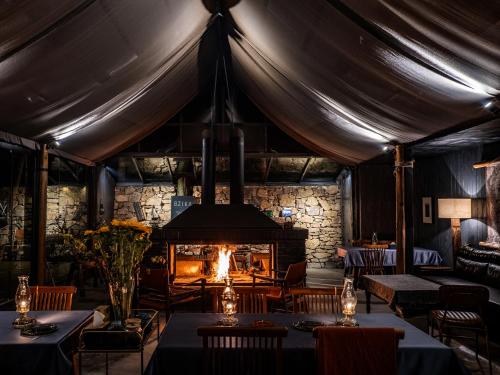 a dining room with a fireplace and tables and chairs at BZIKA Wonderland Retreat--Zhangjiajie National Forest Park Store in Zhangjiajie
