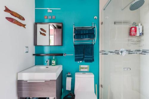a bathroom with a white sink and a blue wall at Savor City Views over Breakfast at a Bold, Bohemian Escape in Mexico City