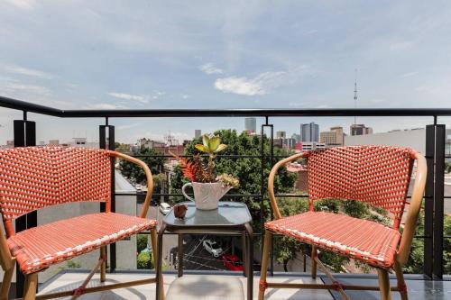 two chairs and a table on a balcony at Savor City Views over Breakfast at a Bold, Bohemian Escape in Mexico City