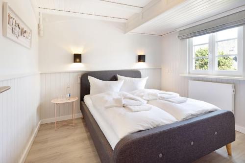 a bedroom with a large bed with white sheets at Buhne 44 in List