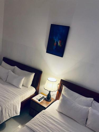 a hotel room with two beds and a lamp on a table at KHÁCH SẠN ROMO in Quang Ngai