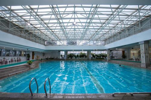 a large swimming pool with blue water in a building at Kunming Golden Spring Hotel in Kunming