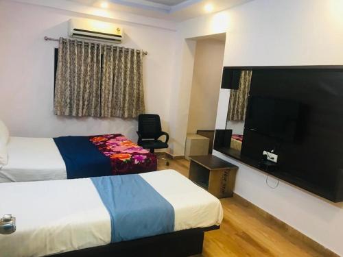 a hotel room with two beds and a flat screen tv at hotel royal night in Ahmedabad
