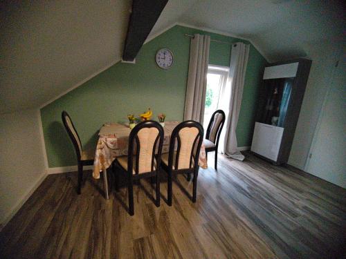 a dining room table with chairs and a clock on the wall at Ferienwohnung im Bergischen Land in Much